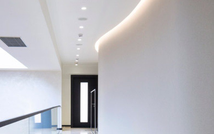 Curved plaster wall along a hallway with recessed ceiling lights
